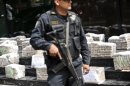 A police officer stands in front of packages of cocaine seized in Peru, during a presentation in Lima, on May 18, 2012
