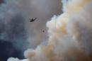 A helicopter flies into thick smoke while battling a major forest fire outside of Fort McMurray