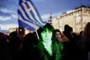 A woman holds a Greek flag as she takes part in an anti-austerity pro-government demonstration in front of the parliament in Athens