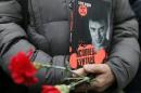 Visitor holds flowers and a book by Russian leading opposition figure Nemtsov before funeral in Moscow