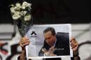 A woman holds up flowers and an image of late prosecutor Alberto Nisman while waiting for the hearse with his remains, in Buenos Aires