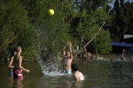 Varios jóvenes se divierten en el río Arga a su paso por Pamplona a la vez que combaten las altas temperaturas registradas ayer en la capital navarra. EFE