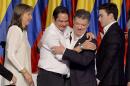 President Juan Manuel Santos, second from right, embraces his running mate German Vargas as first lady Maria Clemencia Rogriguez, left, and his son Martin Santos stand by during their victory rally in Bogota, Colombia, Sunday, June 15, 2014. Santos defeated challenger, Oscar Ivan Zuluaga, of the Democratic Center, and won a second four-year term. (AP Photo/Santiago Cortez)