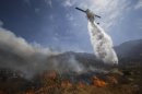 A helicopter drops water over a wildfire on Thursday, Aug. 8, 2013, in Cabazon, Calif. About 1,500 people have fled and three are injured as a wildfire in the Southern California mountains quickly spreads. Several small communities have evacuated. (AP Photo/Jae C. Hong)