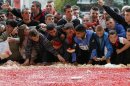 Children eat pieces of a giant cake prepared for the celebration of Albania's 100th Year of Independence in Tirana