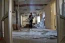A man carries crutches as he walks on glass fragments inside a damaged hospital after what activists said were barrel bombs dropped by forces loyal to Syria's President Bashar al-Assad and fell near the hospital in the town of Tel al-Shehab in Deraa, Syria