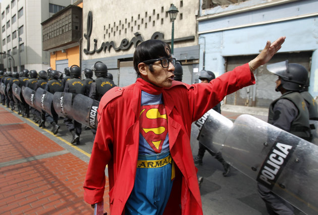 En esta fotografía tomada el 13 de junio de 2012, Avelino Chávez, quien suele vestirse como Superman, saluda a policías antimotines que caminan hacia una plaza donde se esperaba una protesta en el centro de Lima, Perú. (Foto AP/Martín Mejía)