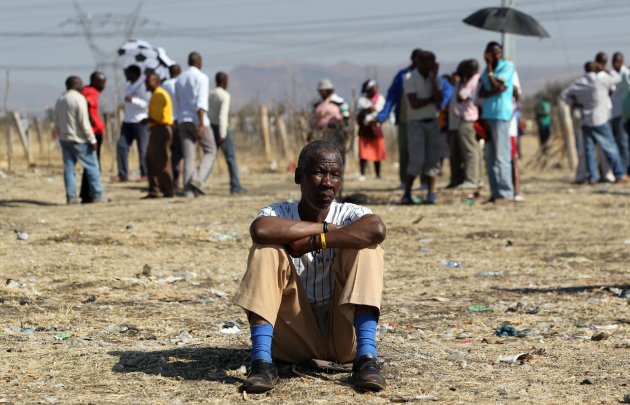 A mine worker Thabo Leribe sits as they wait for a report back from their union at the Lonmin mine near Rustenburg, South Africa, Tuesday, Aug. 21, 2012. Mine workers trickled in Tuesday at the Lonmin platinum mine where 44-people have died in a wildcat strike, as South Africa urged the company to suspend an ultimatum to return to work. (AP Photo/Themba Hadebe)
