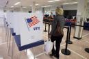 A woman walks past voting booths at the Cuyahoga County Board of Elections in Cleveland, Tuesday, Oct. 7, 2014. Early voting began in Ohio after the U.S. Supreme Court stepped into a dispute over the schedule, pushing the start date back a week in the swing state. (AP Photo/Mark Duncan)