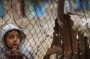Palestinian boy looks through a fence near his family's house, that witnesses said was damaged by Israeli shelling during a 50-day war last summer, in the east of Gaza City