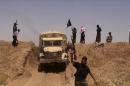 An image made available by the jihadist Twitter account Al-Baraka news on June 11, 2014 allegedly shows militants of the Islamic State group waving the Islamic Jihad flag as a vehicle drives on a newly cut road through the Syrian-Iraqi border