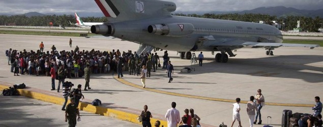 Hundreds of stranded tourists gather around a Mexican Air Force jet as they wait to be evacuated, at the air base in Pie de la Cuesta, near Acapulco, Mexico. (AP/Eduardo Verdugo)